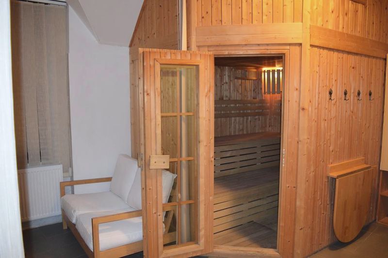 Fínska sauna s otvorenými presklenými dverami a osvetlenými lavicami.